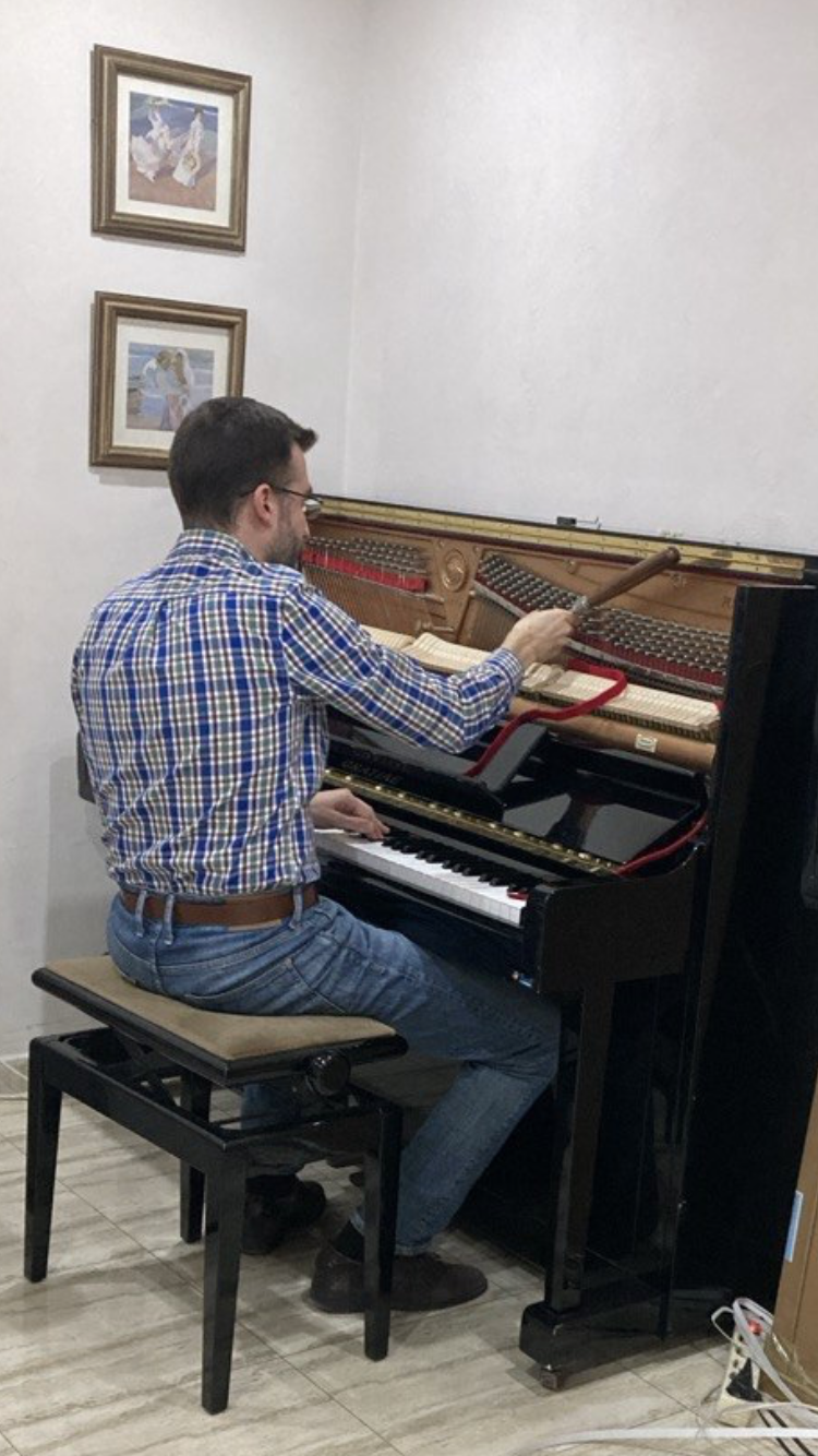 Samuel C. afinando un piano vertical en un domicilio
